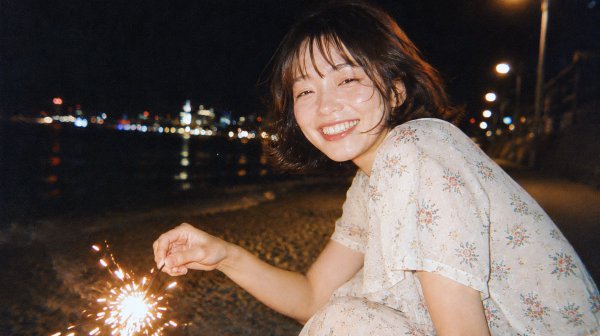 手持ち花火を持ってカメラ目線で笑う若い女性の写真 no.1